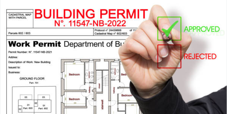 Hand marking a building permit as approved with a green check above floor plans; permit number 11547-NB-2022 is shown in red.